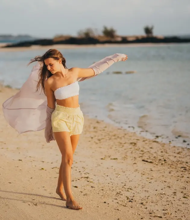 Woman walking alone on the beach, reconnecting with herself in a peaceful moment