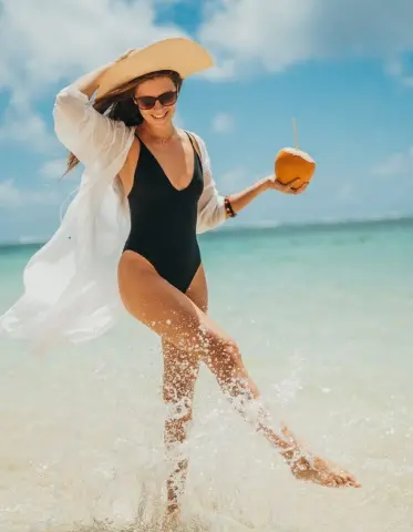 Femme heureuse profitant d’une noix de coco rafraîchissante sur la plage