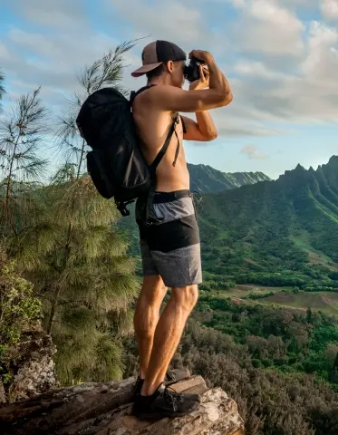Hiker capturing a photo of a vibrant sunset over the landscape of Mauritius from a scenic viewpoint