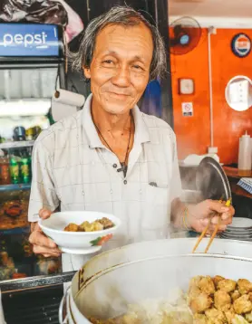 Elderly Mauritian man serving traditional dim sum in a local setting