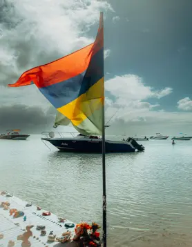 Drapeau de Maurice planté sur une plage de sable avec vue sur l’océan